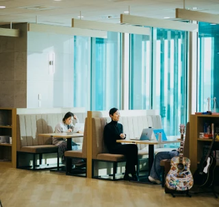 View of SmartHR’s Tokyo headquarters office, showing 2 groups of employees working, chatting, and laughing on sofas by the windows