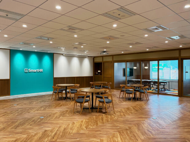 新しい東海オフィスの内観。床はヘリーンボーン調の木材を使用しており、温かみのあるオープンな空間。壁にはSmartHRのロゴが飾られています。