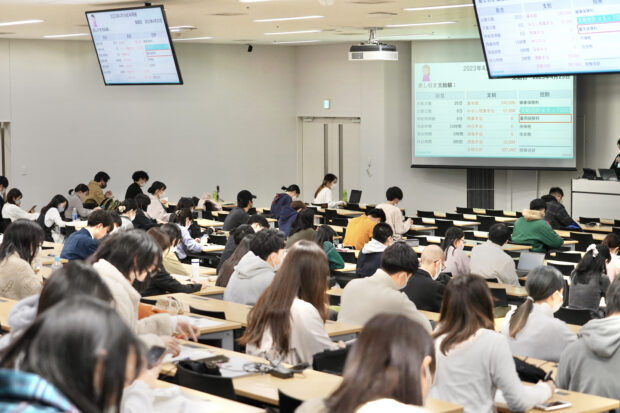 大学の教室いっぱいに学生が着席し、熱心に講座を受講している様子が映った写真