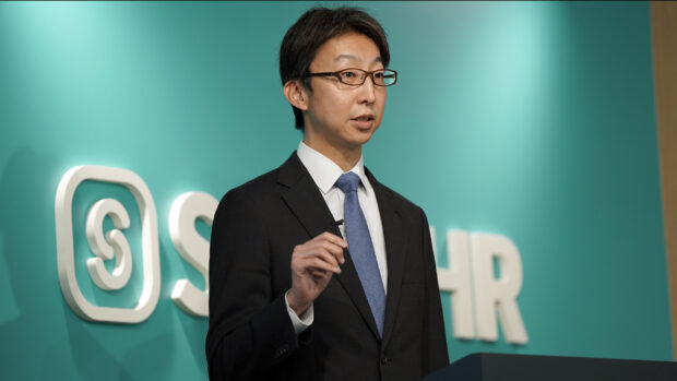 SmartHRのロゴを背景に登壇する取締役COO倉橋のバストアップ写真